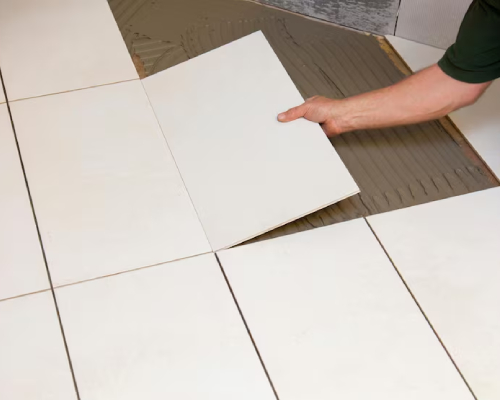 Tiler prepping and grouting surface during bathroom tiling